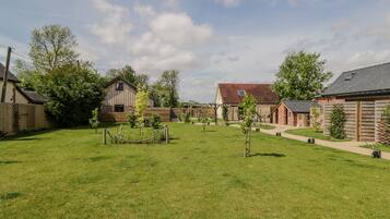 A spacious backyard with a well-maintained lawn, a wooden fence, and several small trees.
