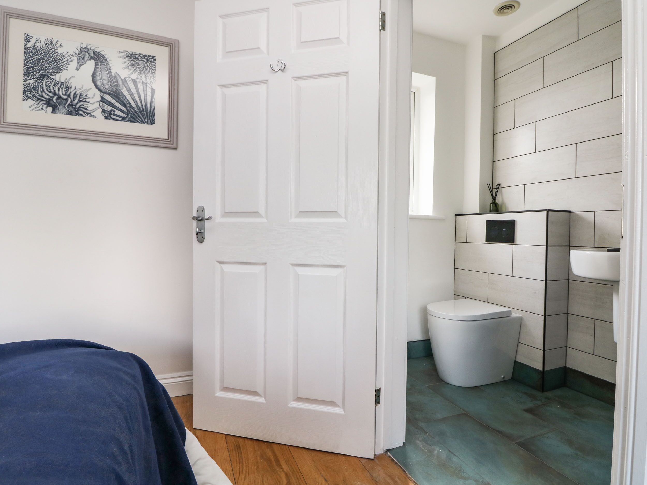 A room with a bed, a white door, a bathroom with a toilet, and a sink.