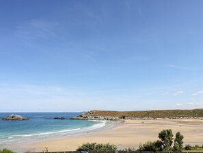 A coastal beach scene with clear skies, sandy shore, rocky outcrops, and sparse vegetation. - Trevose House (Newquay)