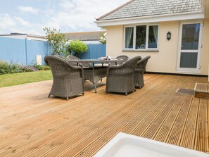 A patio with a dining table and chairs, a small white sink, and a blue fence in the background. - Trevose House (Newquay)