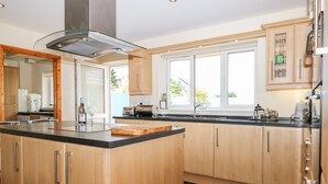 Eine moderne Küche mit einer großen Kochinsel, Edelstahlgeräten und einem Fenster, das für natürliches Licht sorgt.