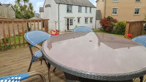 A round table with wicker chairs in a backyard setting. - Fistral Bay Cottage (Newquay)