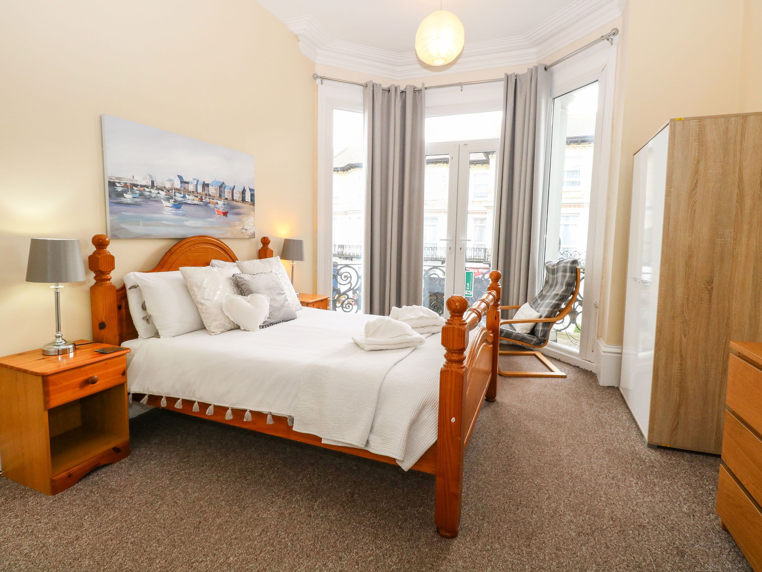 A neatly arranged hotel room with a bed, bedside tables, a chair, and a wardrobe.