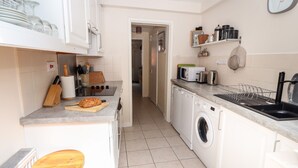 A compact kitchen with a built-in washing machine, a microwave, and a sink. - Tower View Cottage (Chester)