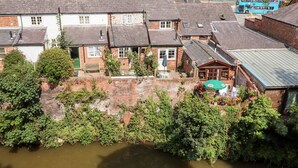 A riverside residential area with brick houses, a pub, and a blue double-decker bus. - Tower View Cottage (Chester)