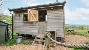 A rustic wooden cabin with a chimney, a small porch, and a wooden table. - Shepherd's Hut (Scarborough)