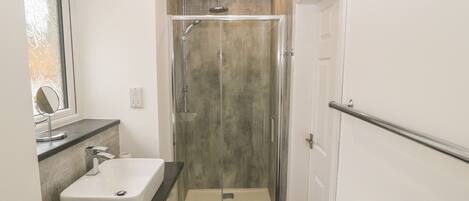 A modern bathroom with a glass-enclosed shower, a white sink, and a mirror.