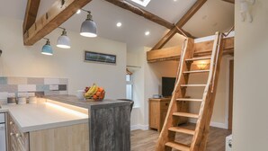 A kitchen with a wooden island, pendant lights, a fruit basket, and a wooden ladder. - Glan Meon Cottage (Barmouth)