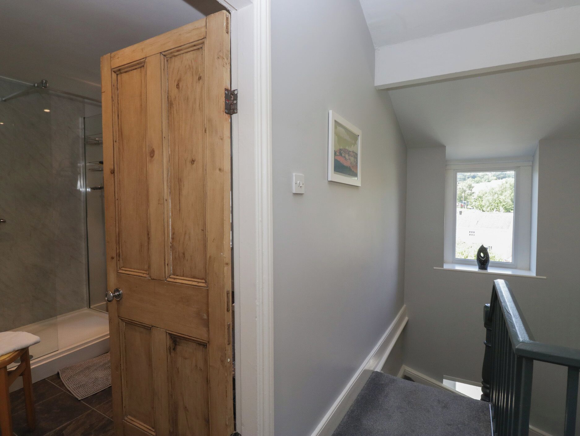 A bathroom with a wooden door, a shower, and a bench.