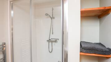 Una ducha con cerramiento de vidrio, un cabezal de ducha manual y un grifo empotrado en la pared.