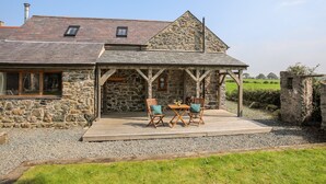 A stone house with a covered patio and outdoor seating. - Ty Cerrig (Gaerwen)