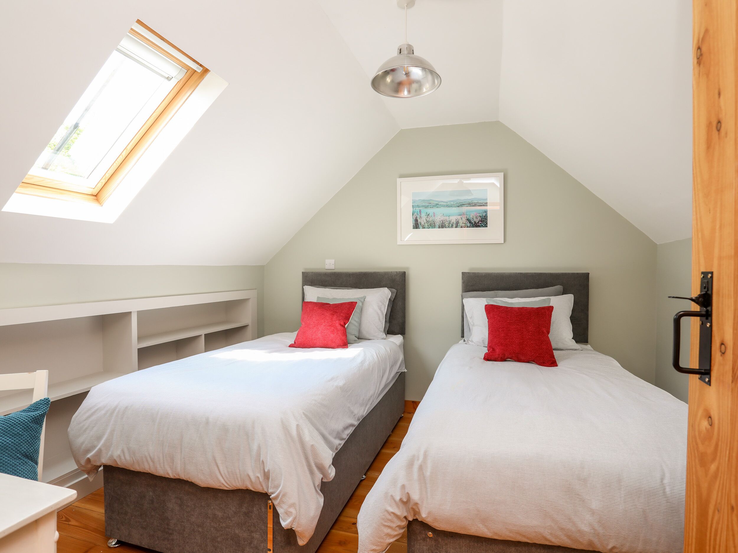 A bedroom with two beds, a skylight, a pendant light, and a framed picture on the wall.