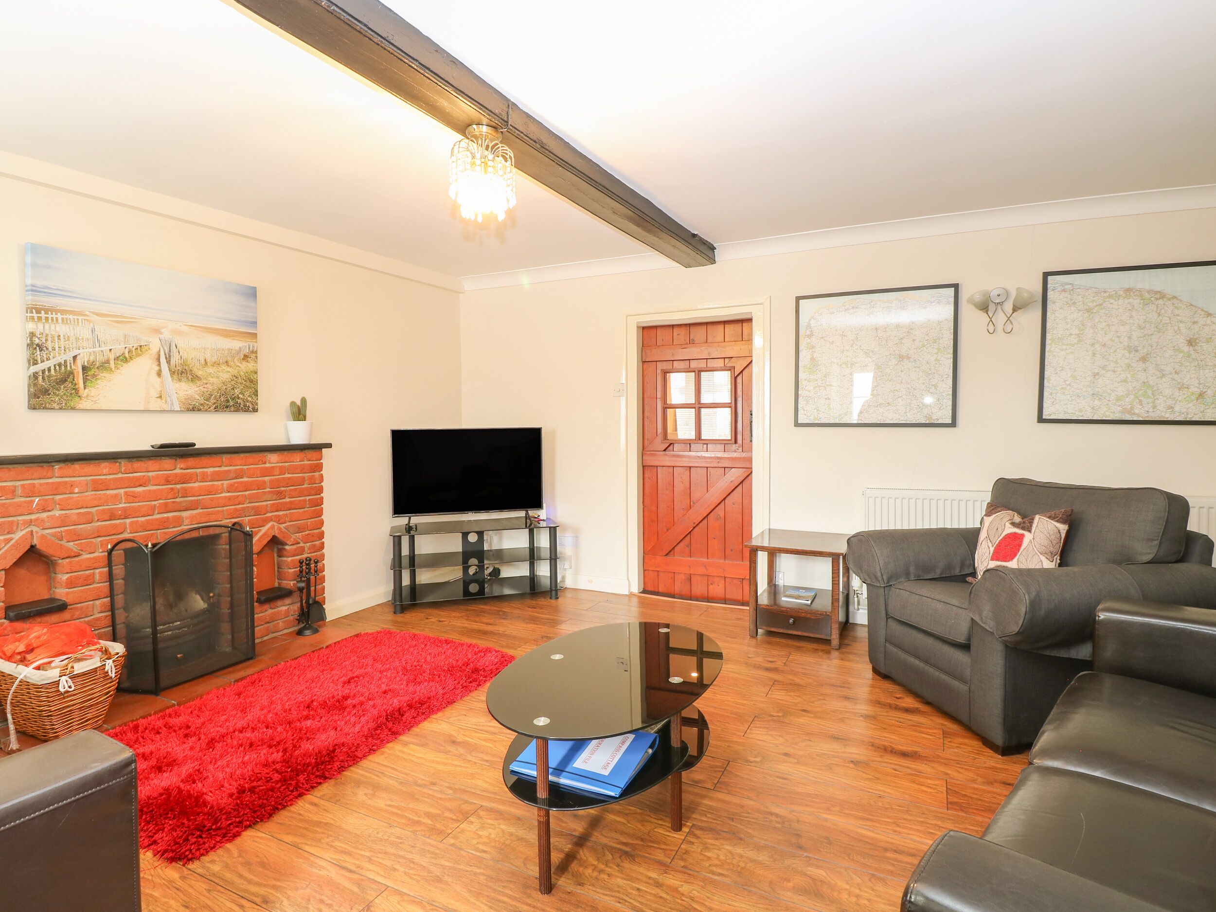 A living room with a fireplace, a television, a sofa, and a red rug.