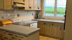 Eine Küche mit Holzausstattung, einer gefliesten Spritzschutzleiste, einem Fenster mit Blick auf die Landschaft und einer Ziegelwand.