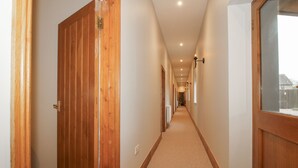 Ein Korridor mit Holztüren, Teppichboden und Einbaustrahlern.