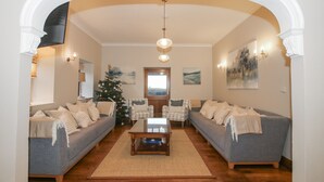 Ein Wohnzimmer mit zwei Sofas, einem Couchtisch, einem Weihnachtsbaum und Kunstwerken an den Wänden.