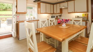 Una cocina con armarios de madera, una mesa de comedor con sillas, un microondas y una ventana con vistas a la vegetación.