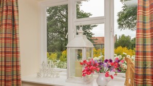 Una ventana con un farol blanco, un jarrón con flores y un letrero que dice "All is Love".