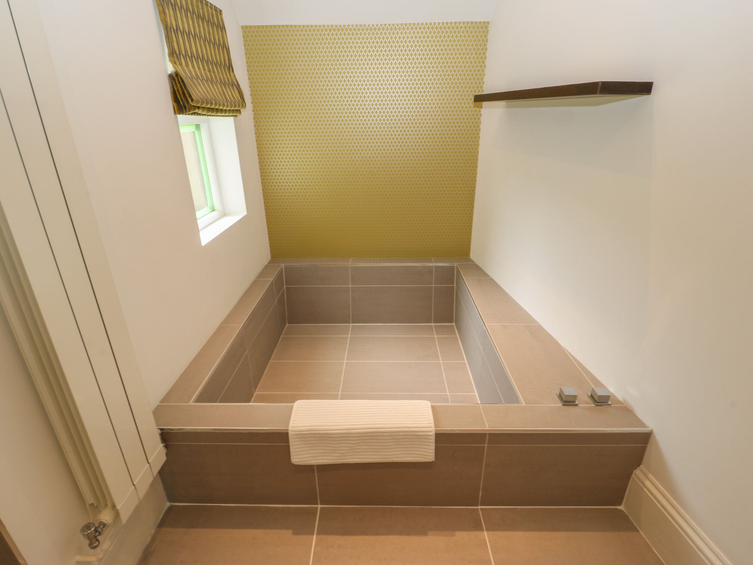 Un baño con bañera, ventana y un perchero para toallas.