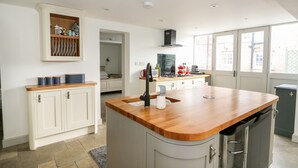 A modern kitchen with a wooden island, white cabinetry, and a view to the outside.
