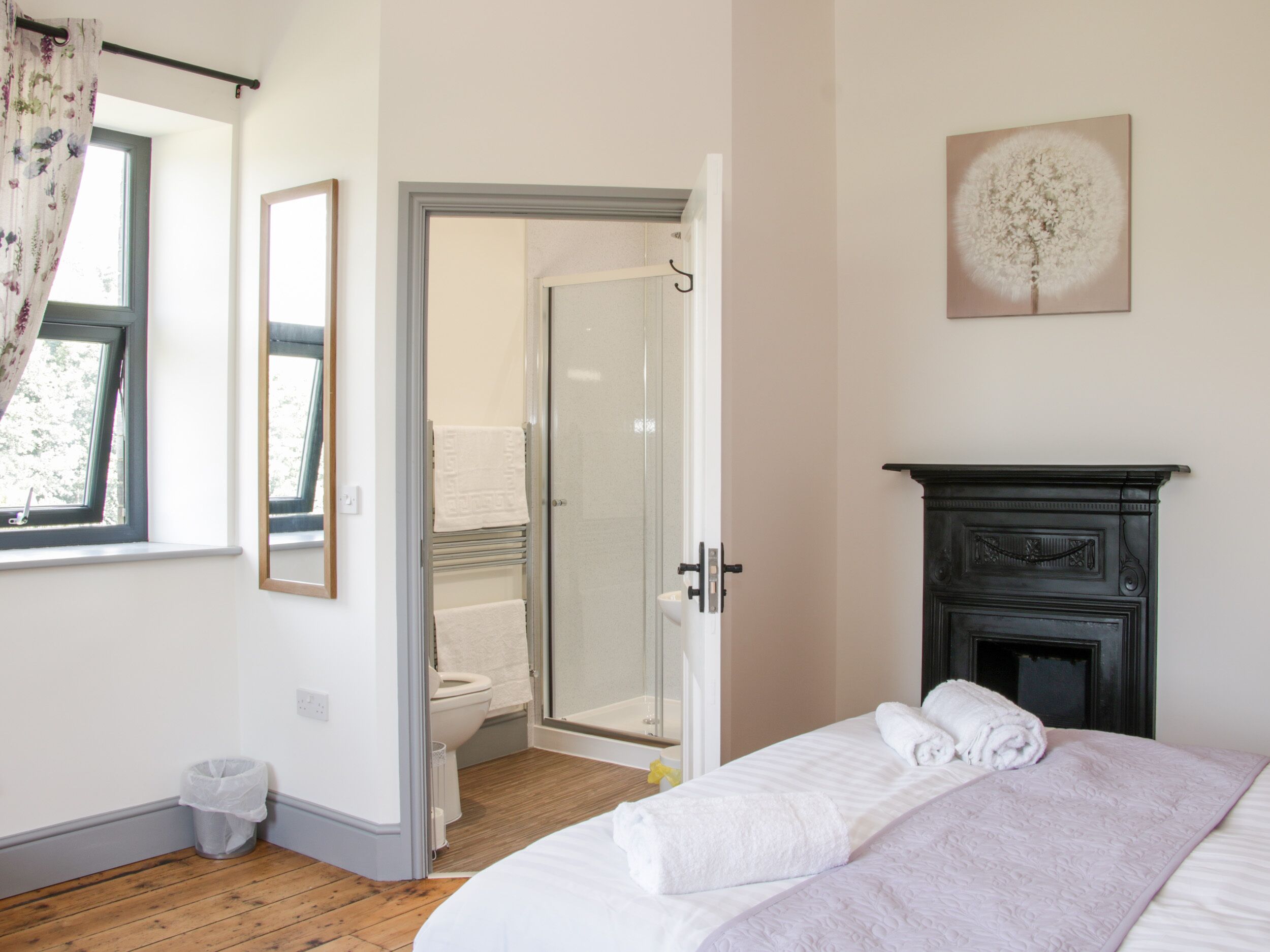 A bedroom with a bed, a fireplace, a shower, and a door leading to a bathroom.