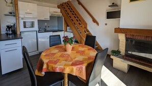 Una cucina compatta con elettrodomestici moderni, una zona pranzo con tavolo e sedie, e un caminetto.
