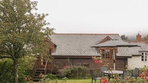 A wooden house with a sloped roof and a small deck. - Flora's Barn (Taunton)