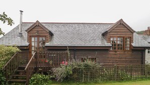 A wooden cabin with a sloped roof, a chimney, and a wooden staircase leading to a door. - Flora's Barn (Taunton)