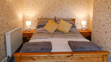 A neatly made bed with two pillows, a bedside lamp, and a wooden headboard.
