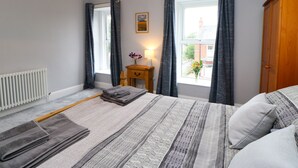 A bedroom with a bed, a bedside table with a lamp, a window with curtains, and a radiator. - Stang View (Barnard Castle)