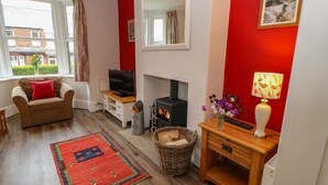 A living room with a sofa, TV, fireplace, and a red accent wall. - Stang View (Barnard Castle)
