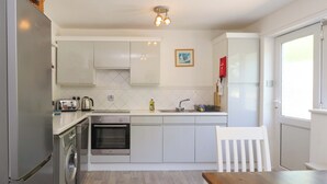 Una cocina moderna con electrodomésticos de acero inoxidable, una mesa de madera y una silla blanca.