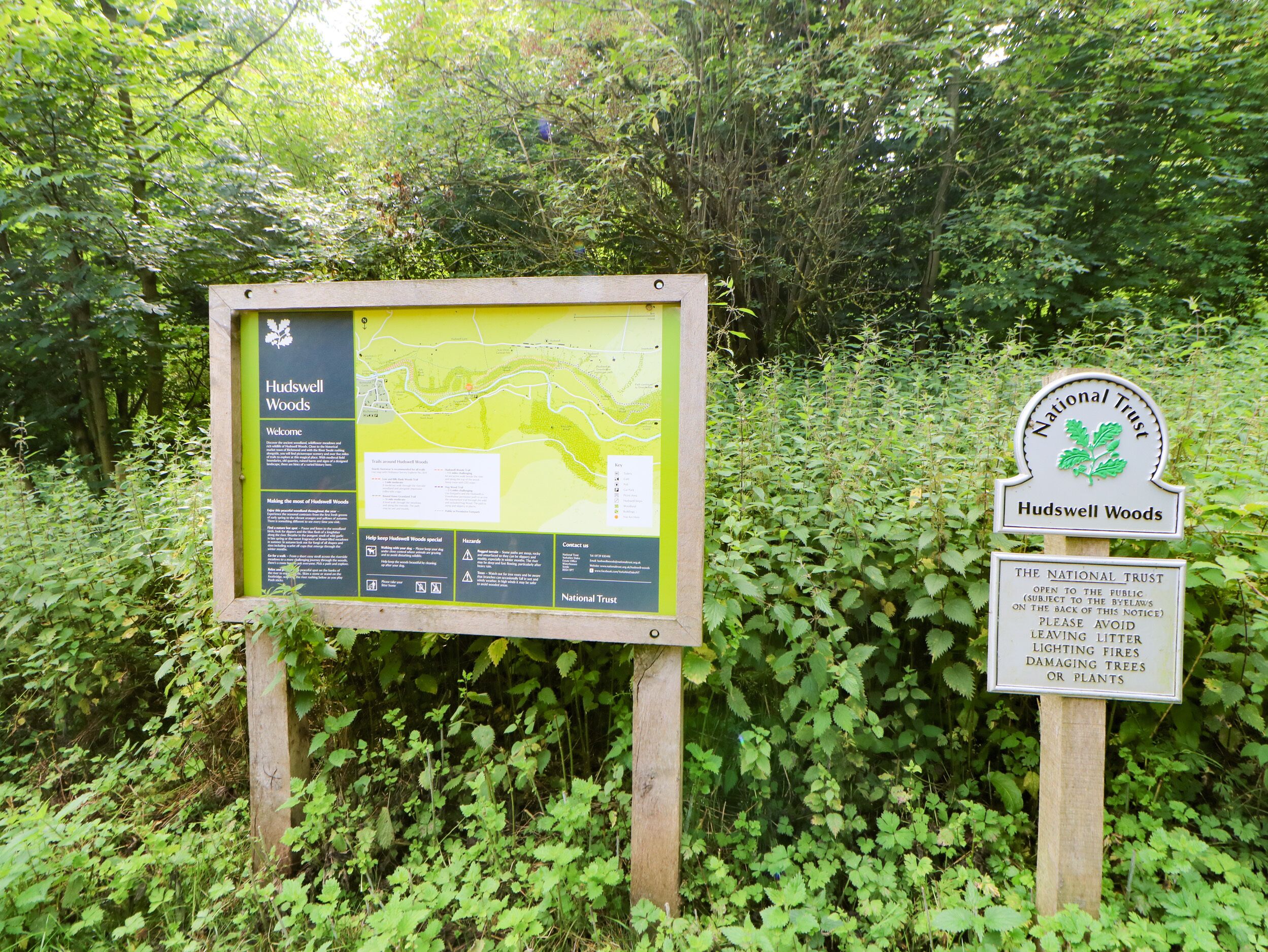 A signboard with information about Hudswell Woods, including a map and visitor guidelines.
