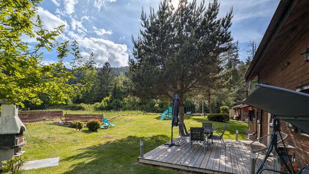 A backyard with a wooden deck, a grill, a swing set, and a slide. - Cozy Chalet by the Stream: Terrace, BBQ, Near Skiing & Cycling Paths, Pet Friendly (Vagney)
