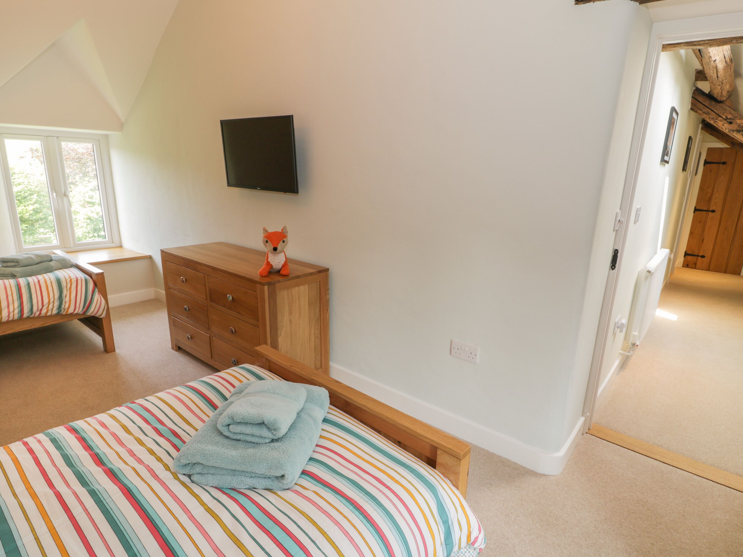 A bedroom with a bed, a dresser, a television, and a window.