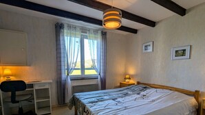 Une chambre à coucher comprenant un lit, un bureau, une chaise et deux lampes de chevet.