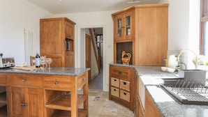 Een keuken met houten kastjes, granieten aanrechtbladen en een inbouwvaatwasser.