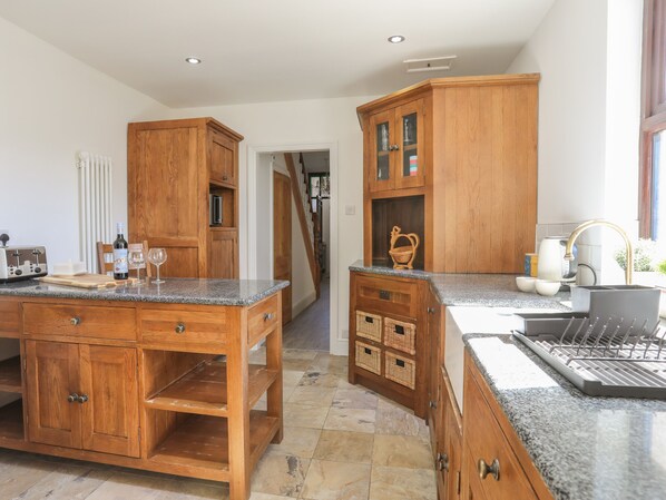 A kitchen with wooden cabinetry, granite countertops, and a built-in dishwasher.