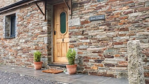 A stone building with a wooden door and a sign that reads "Elvan Cottage." - Elvan Cottage (Liskeard)