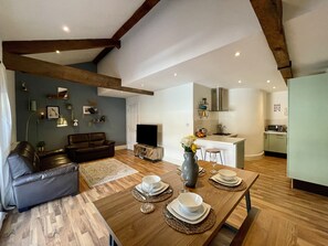 A modern living room with a sofa, a dining table set for four, and a kitchen area with a microwave and cabinets. - The Bell Tower (Inverness)