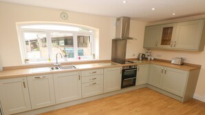 A kitchen with a window, sink, stove, oven, and cabinets. - Woodpecker Barn (Pontyclun)