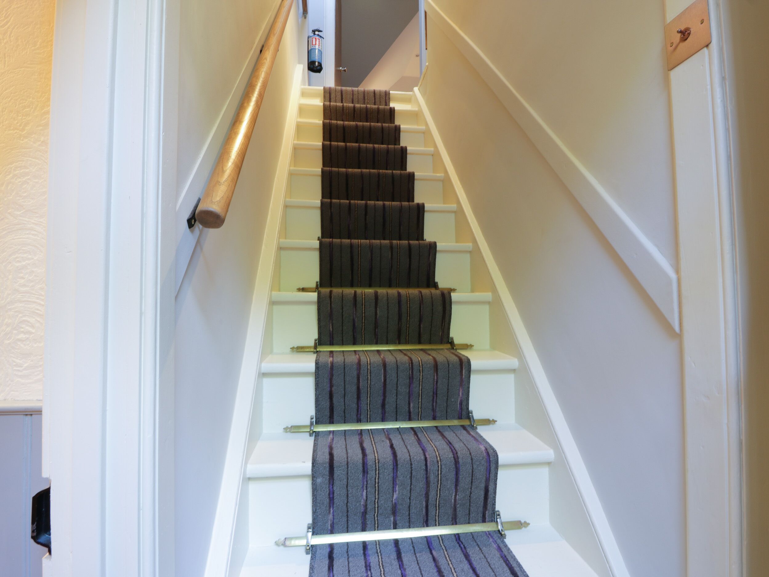 A staircase with a striped carpet and white walls.