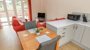 A compact kitchen with a dining area, a TV, and a microwave. - Nuthatch Barn (Pontyclun)