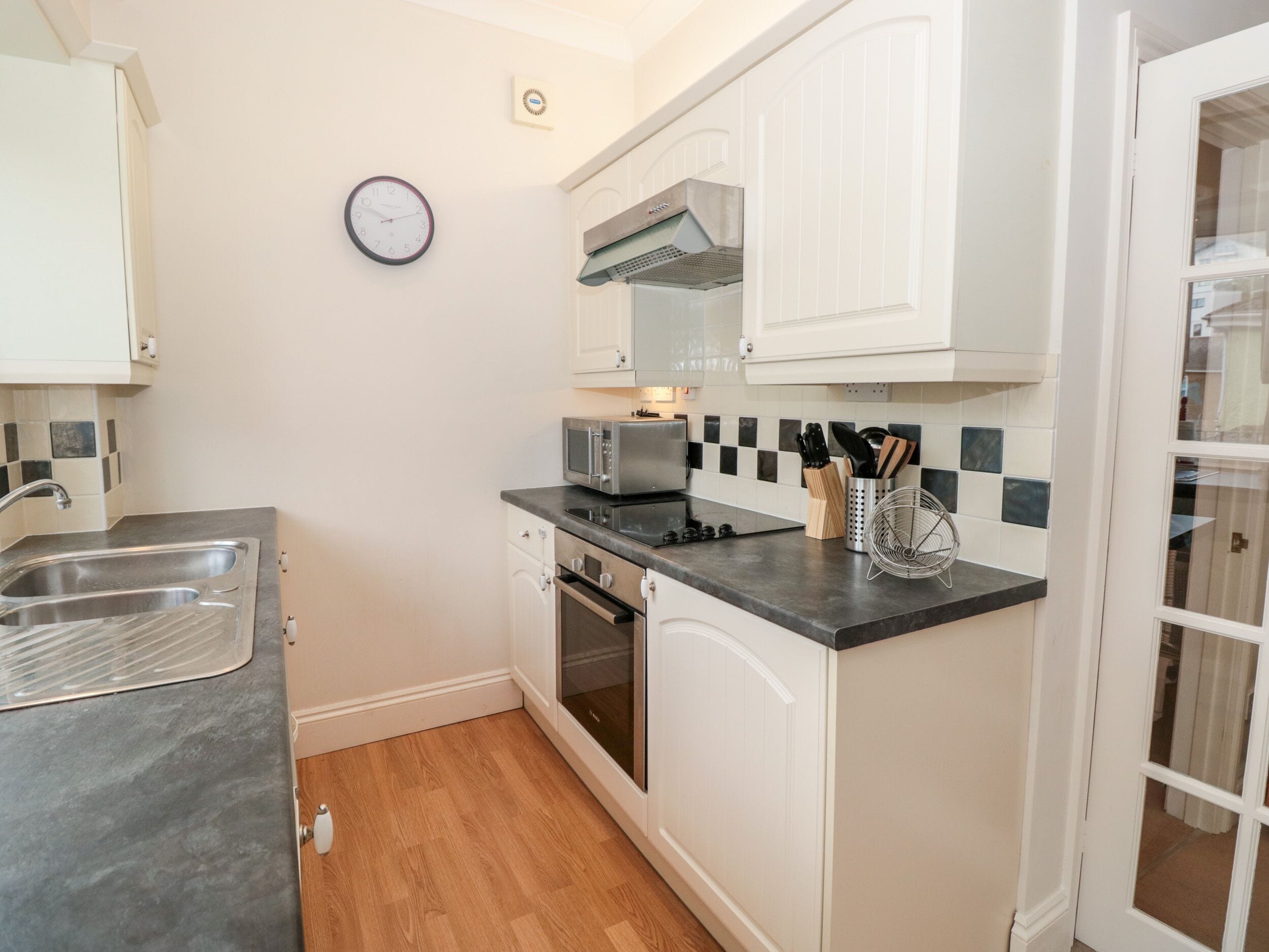 A compact kitchen with white cabinets, a microwave, a toaster, and a sink.