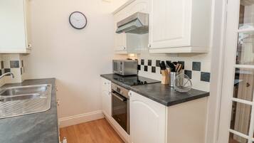 A compact kitchen with white cabinets, a microwave, a toaster, and a sink.