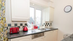 A kitchen with white cabinets, a black countertop, a red kettle, a red toaster, and a sink. - Huffin (Dartmouth)
