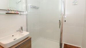 A modern bathroom with a glass-enclosed shower, a white sink, and a wooden vanity.