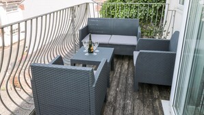 A balcony with wicker furniture, a bottle of champagne, and glasses. - Huffin (Dartmouth)