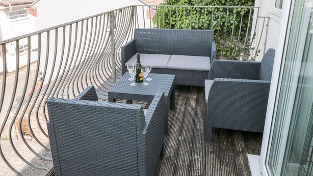 A balcony with wicker furniture, a bottle of champagne, and glasses.