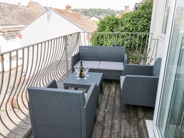 A balcony with wicker furniture, a bottle of champagne, and glasses. - Huffin (Dartmouth)